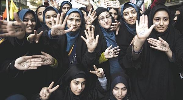 شابات إيرانيات كتبن على أيديهن شعارات معادية للولايات المتحدة منها «تسقط أميركا» و«الموت لأميركا» وسط طهران أمس (أ.ف.ب)