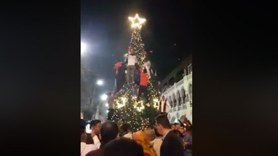 بالفيديو.. شباب يتسلقون شجرة الكريسماس في ميدان الكوربة