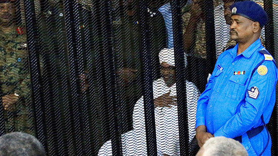 الرئيس السوداني السابق عمر حسن البشير يجلس في حراسة داخل قفص في المحكمة حيث يواجه تهما بالفساد 