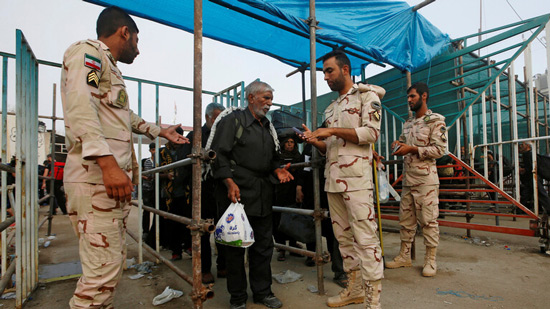 عناصر من حرس الحدود الإيراني يفتشون حاجا متجها إلى العراق لزيارة الأربعين