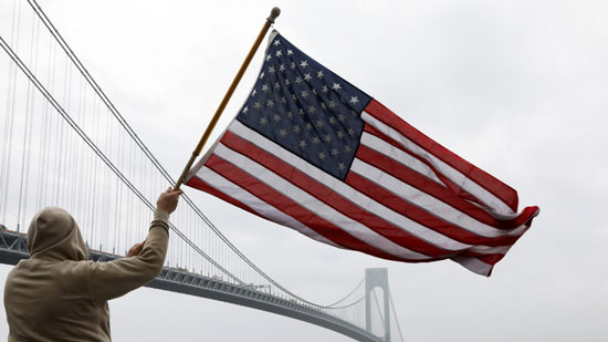 رجل يمسك علم الولايات المتحدة في نيويورك في زمن جائحة فيروس كورونا